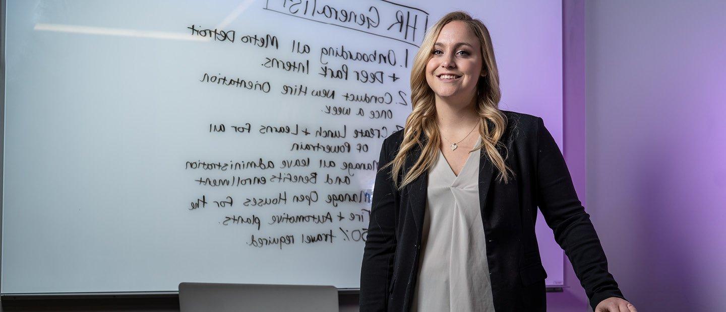 A young woman standing in front of a white board with 